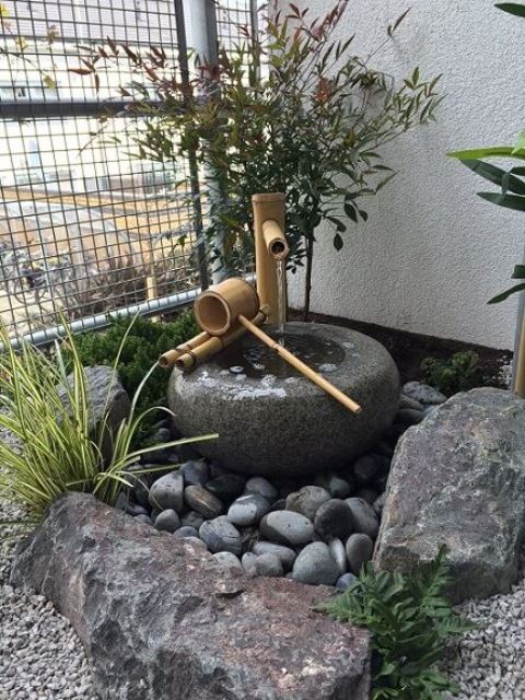 rocce, ciottoli, una tradizionale fontana in pietra e bambù, vegetazione tra le rocce compongono un piccolo e grazioso cortile