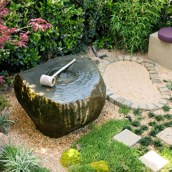 erba, ciottoli, mattoni e una fontana in pietra con una paletta di legno per un'atmosfera giapponese informale e rilassata in giardino