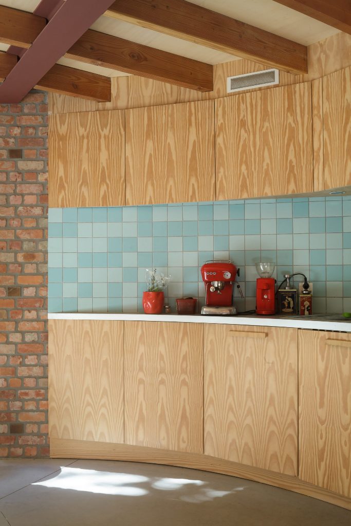 Le piastrelle blu bicolore formano un paraspruzzi della cucina e gli elettrodomestici rosso vivo contribuiscono a creare un'atmosfera moderna della metà del secolo