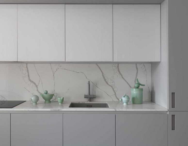 La cucina è realizzata in due tonalità di grigio, con alzatina in marmo e ripiani
