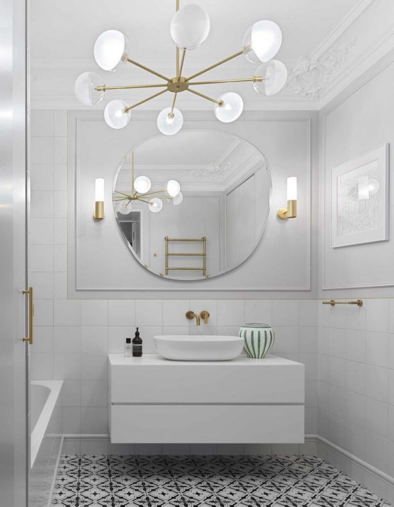 Un altro bagno è realizzato in bianco, con un pavimento a motivi geometrici in bianco e nero, lampade chic ed eleganti e tocchi in ottone