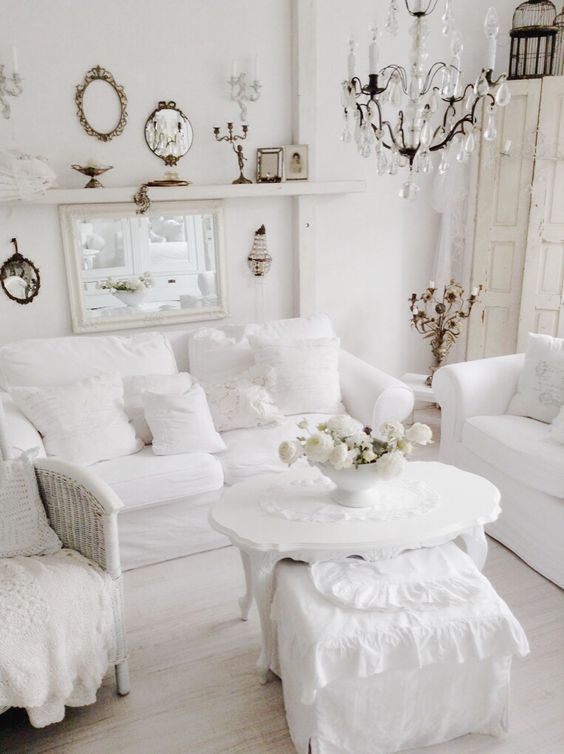 un soggiorno shabby chic bianco puro con mobili eleganti, un lampadario di cristallo, specchi e candele è wow