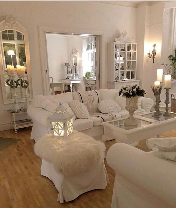 uno spazio di vita bianco shabby chic con specchi eleganti e mobili in stile, candele, lanterne a candela e fiori bianchi