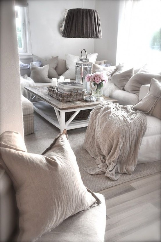 un soggiorno shabby chic neutro e imbiancato con mobili semplici ed eleganti, un tavolo basso e lampade a sospensione