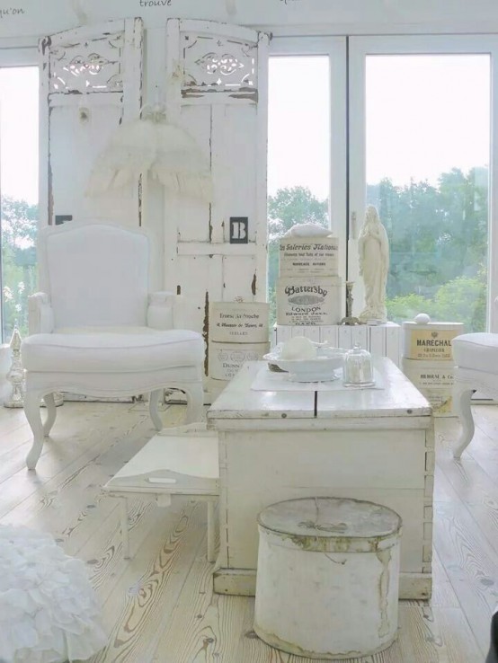 un soggiorno shabby chic bianco con mobili eleganti, paravento in legno intagliato, ali d'angelo e accessori antichi