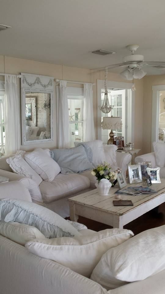 un soggiorno shabby chic neutro con pareti dai colori caldi, mobili e cuscini neutri, un lampadario di perline e tocchi pastello qua e là