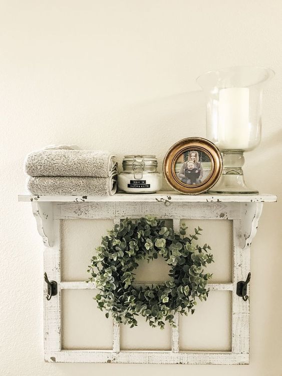 una mensola fresca e facile di una vecchia cornice di una finestra, con una ghirlanda verde, una candela, una foto, alcune coperte è l'ideale per un bagno