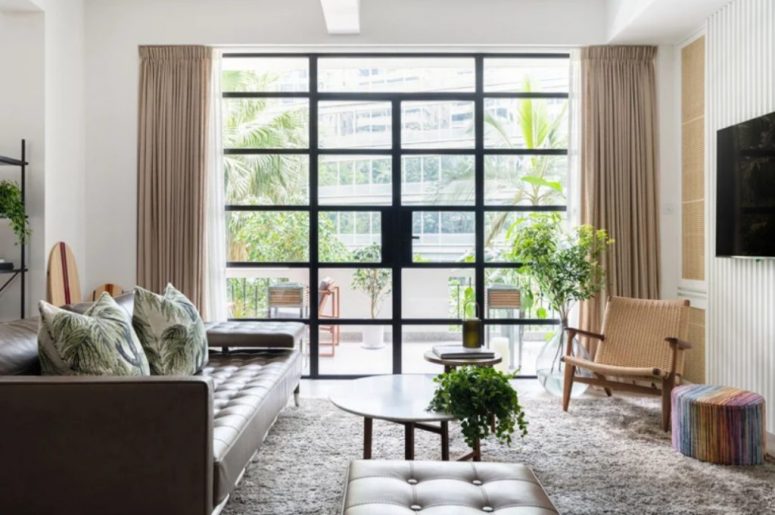 Il soggiorno è realizzato con un divano in pelle e un pouf, con una sedia intrecciata e una parete vetrata che fa da ingresso a una terrazza
