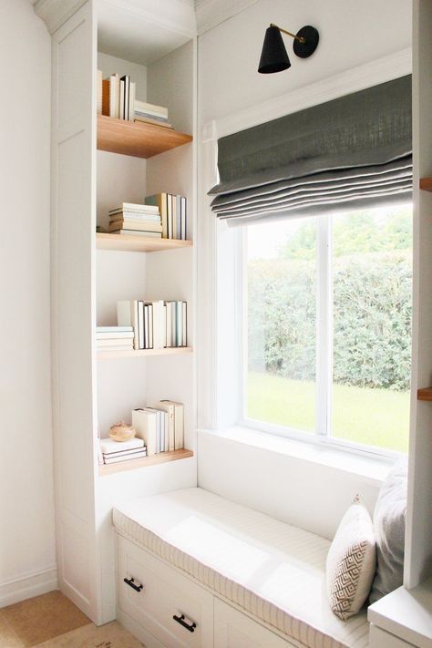 un accogliente sedile della finestra con librerie incassate su entrambi i lati e una tenda grigia è uno spazio elegante
