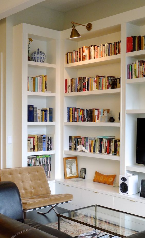un elegante soggiorno moderno della metà del secolo con scaffali per libri incorporati e lampade aggiuntive nello spazio