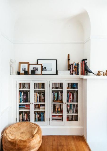 librerie da incasso con ante in vetro e un piccolo pouf per un accogliente angolo lettura