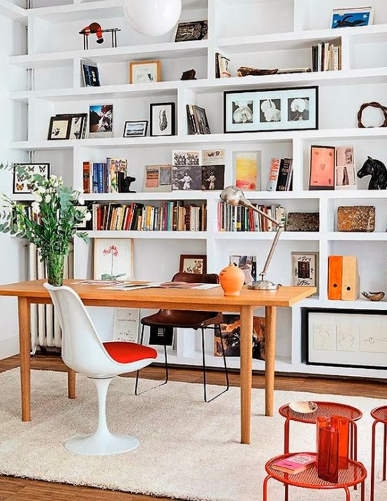 un ufficio domestico accogliente e luminoso con un'intera parete di librerie componibili e alcuni mobili è uno spazio fresco in cui lavorare