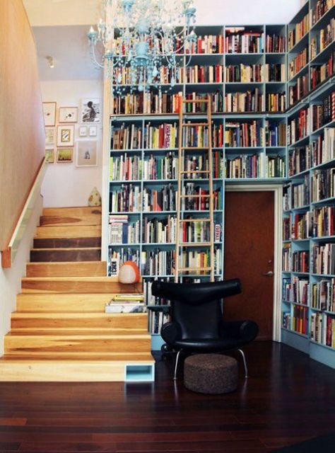 una libreria d'ingresso coperta con scaffali incorporati, con un lampadario vintage e una sedia nera è incredibile per sfruttare il tuo spazio
