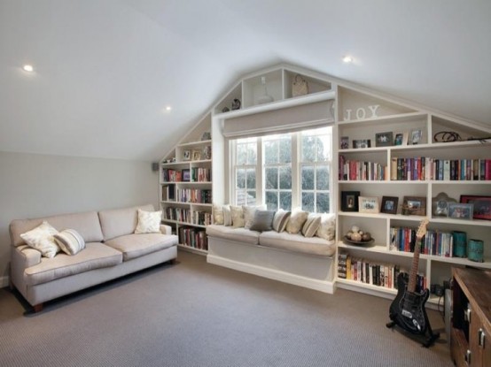 una mansarda neutra con scaffali per libri incorporati intorno alla finestra: è un bel modo per riporre le cose e risparmiare spazio