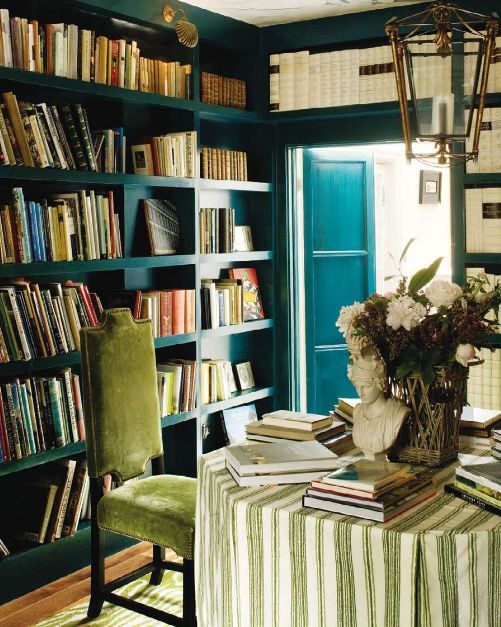 una raffinata libreria domestica con scaffali blu incorporati che coprono tutte le pareti è un'idea molto elegante e alla moda