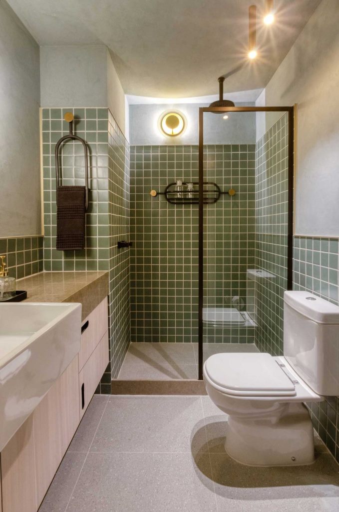 Il bagno continua il tema moderno della metà del secolo nell'arredamento con le sue piastrelle verdi opache e le superfici neutre