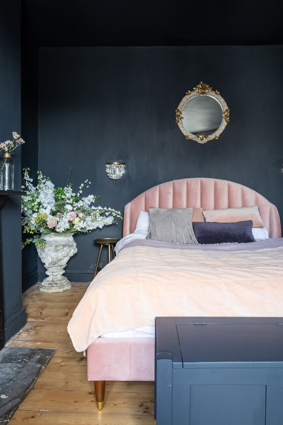 un'elegante camera da letto lunatica con pareti nere e una cassettiera per riporre oggetti, un letto rosa chiaro, luci raffinate e fiori