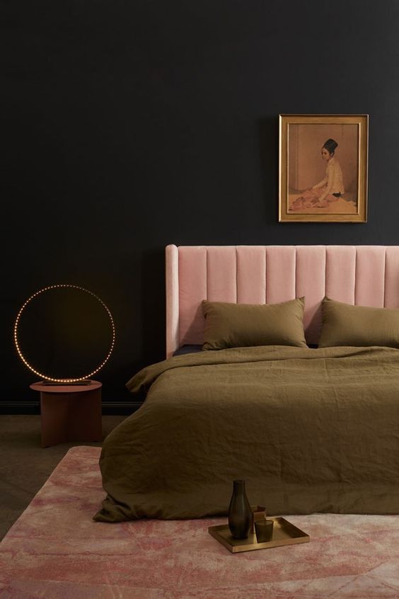una camera da letto lunatica e raffinata con pareti nere, un letto arrossato, un'opera d'arte vintage, biancheria da letto verde, una lampada da tavolo audace