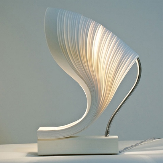 una lampada da tavolo scultorea unica con una base bianca, un paralume bianco materico per uno spazio minimalista