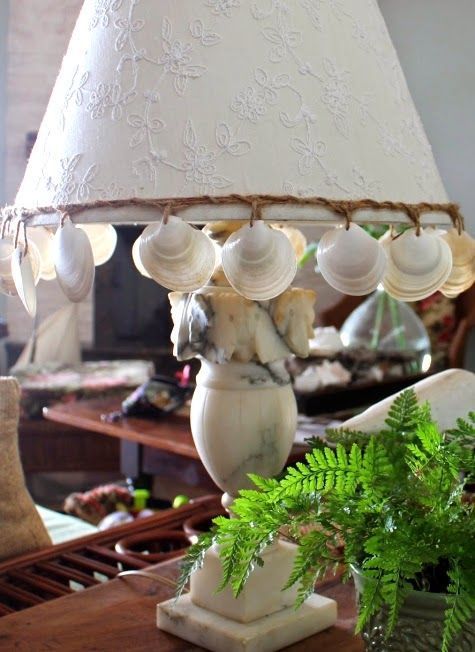un'accattivante lampada da tavolo in pietra sul mare, con conchiglie appese al paralume è un'idea fresca e audace