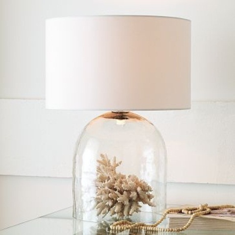 una lampada da tavolo unica con un corallo in una cloche come base e un semplice paralume per uno spazio sul mare