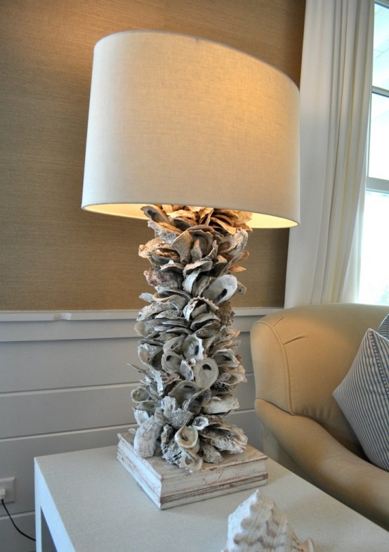 un'elegante lampada da tavolo con una base di conchiglie e una normale tonalità attira l'attenzione e sembra molto ispirata al mare