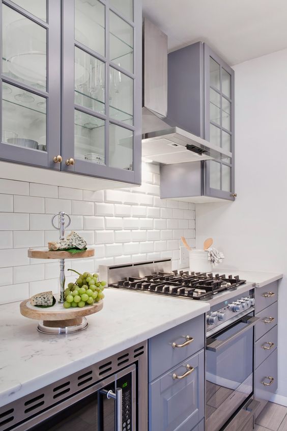 un'elegante cucina lilla con un backsplash in piastrelle bianche della metropolitana e ripiani in pietra bianca sembra molto romantica