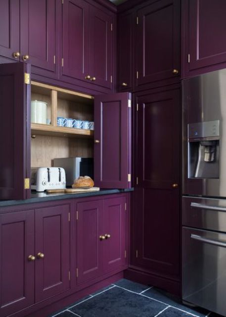 una lunatica cucina vintage viola, tutta rivestita di ante e pannelli e con pomelli dorati per un accento