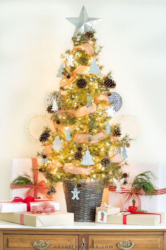 un albero di Natale bello e chic in un cestino, con pigne, mini ornamenti a forma di albero, fiocchi di neve e luci più un cappello a cilindro a stella