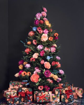 un bellissimo e colorato albero di Natale decorato con finte fioriture in tutte le sfumature possibili è un'idea cool fuori dagli schemi