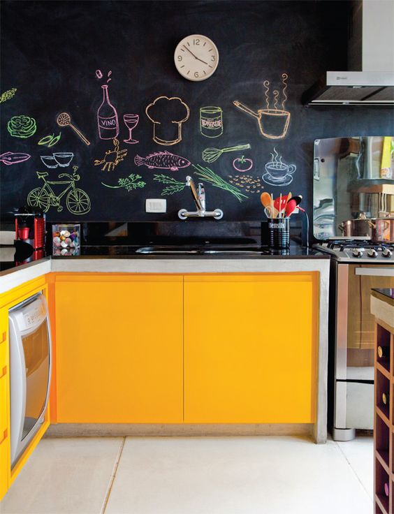 una cucina luminosa in giallo con pareti a lavagna che creano un contrasto e rendono lo spazio accattivante e audace grazie all'arte dei colori