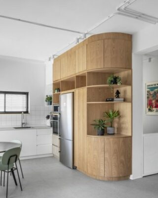 La cucina, la zona pranzo e il soggiorno sono combinati in un ampio spazio aperto con pavimento grigio chiaro, pareti bianche e accenti di mobili in rovere