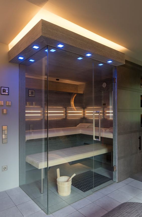 una sauna moderna e fresca rivestita di pietra scura e legno chiaro, con un paio di panchine e luci incorporate