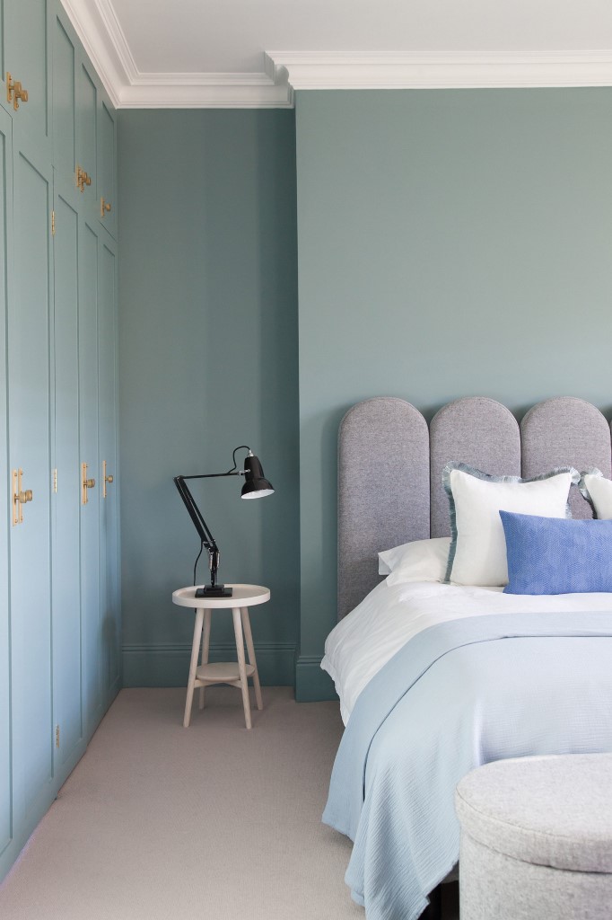 La camera da letto principale sfoggia pareti blu polvere e mobili imbottiti di nuovo accattivanti