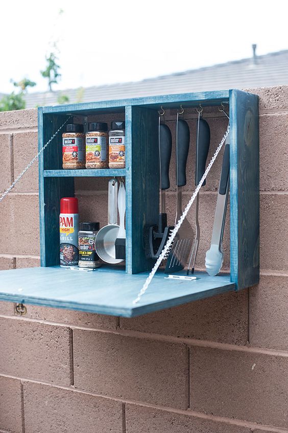 una scatola di immagazzinaggio blu con un tavolo pieghevole sarà una bella aggiunta al tuo angolo barbecue all'aperto