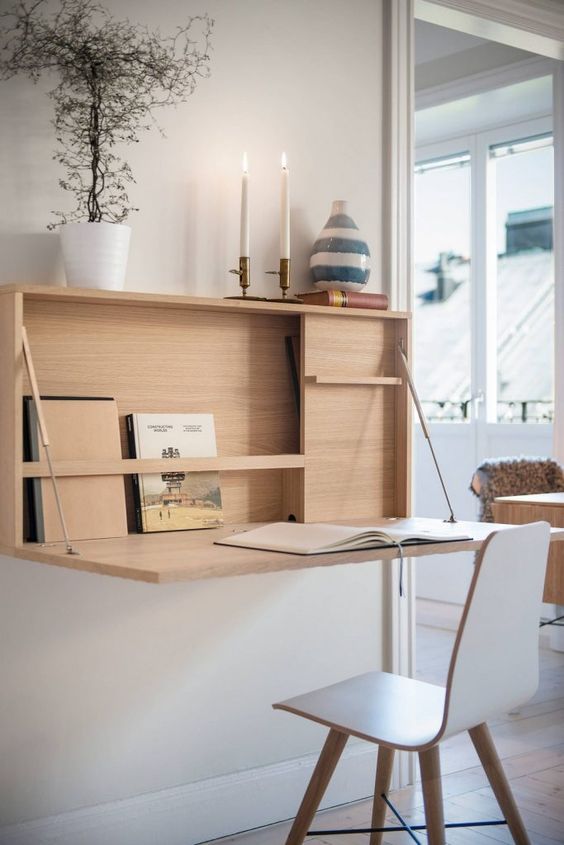 una scrivania minimalista a parete con spazio di archiviazione all'interno, alcune candele e una superficie della scrivania che può essere nascosta