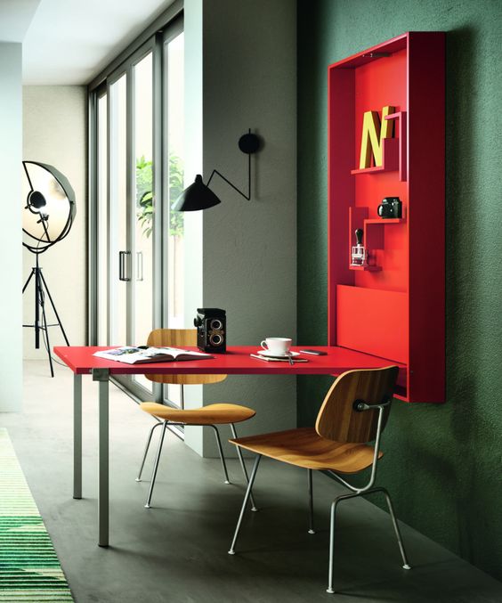 una scrivania pieghevole rosso caldo o una sala da pranzo con alcuni ripiani all'interno è un'opzione interessante per un piccolo spazio