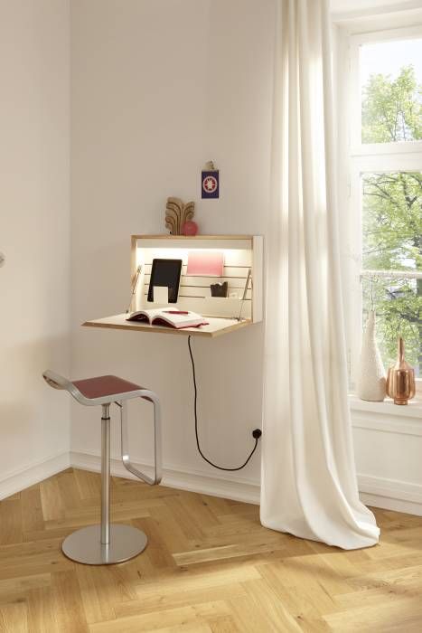 una mini scrivania pieghevole a parete con luci incorporate e con libri e altre cose necessarie