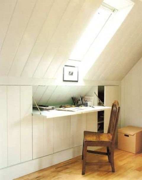 una piccola scrivania bianca incorporata nell'inclinazione della soffitta dello spazio sotto il lucernario è un'idea interessante
