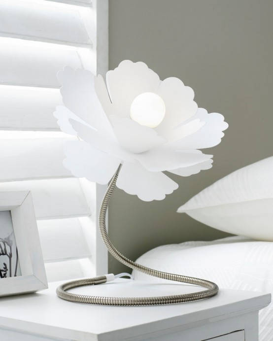 una lampada da tavolo bianca a forma di fiore in metallo con un grande paralume è un'aggiunta creativa a una camera da letto