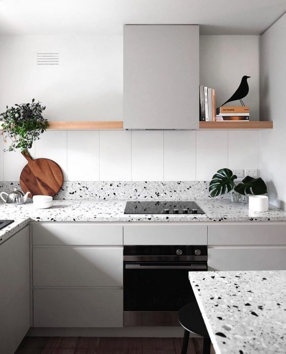 una cucina minimalista in tortora accentuata con un piano di lavoro in terrazzo grigio e alzatina più un tavolo abbinato qui