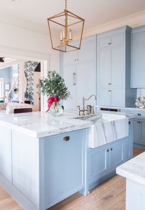 una bella ed elegante cucina azzurra con ripiani in marmo bianco che fanno una dichiarazione di lusso accentuando i colori