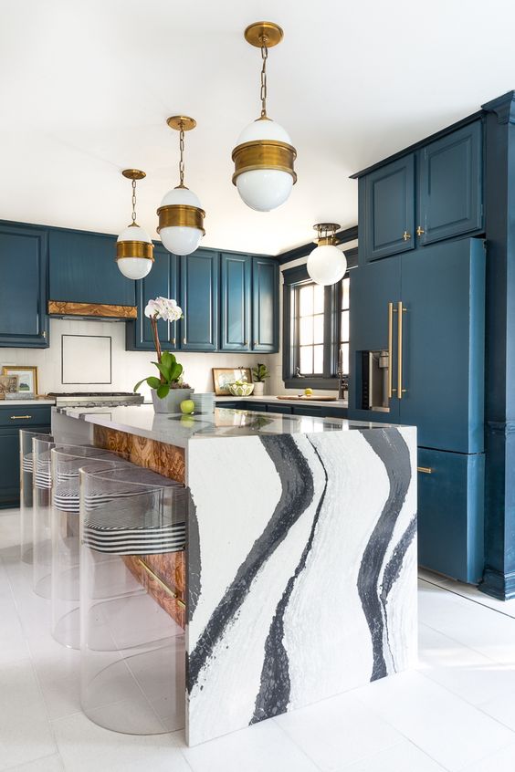 un'elegante cucina blu e un'isola cucina con uno splendido piani di lavoro a cascata in marmo bianco che fa una dichiarazione qui