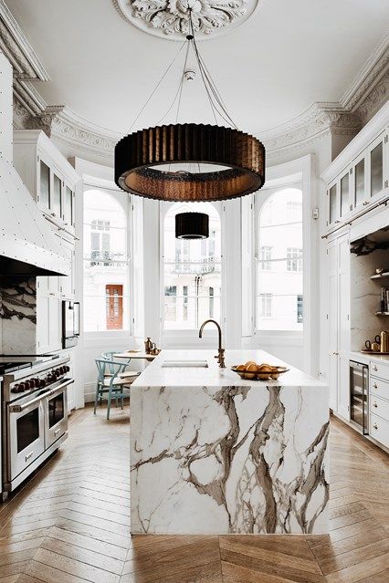una lussuosa cucina bianca con una grande isola della cucina e un fantastico piano di lavoro in marmo bianco che stupisce immediatamente