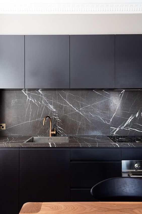 una cucina minimalista blu notte con un backsplash e un piano di lavoro in marmo nero che gli conferiscono un aspetto e una sensazione di lusso