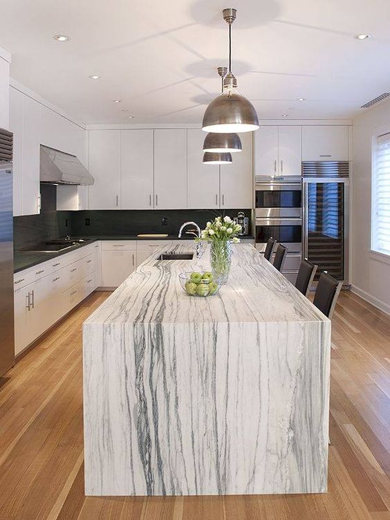 una cucina monocromatica con una splendida isola cucina che presenta un piano di lavoro in marmo bianco e fa una dichiarazione
