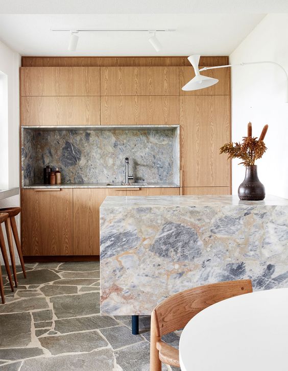una piccola cucina di colore chiaro con alzatina in marmo grigio e Top cucina tra cui uno a cascata che oscilla