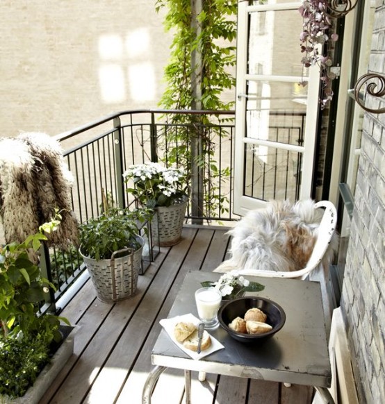 un balcone neutro per l'estate con piante in vaso e fiori, mobili in metallo, coperture in pelliccia sintetica per sedie