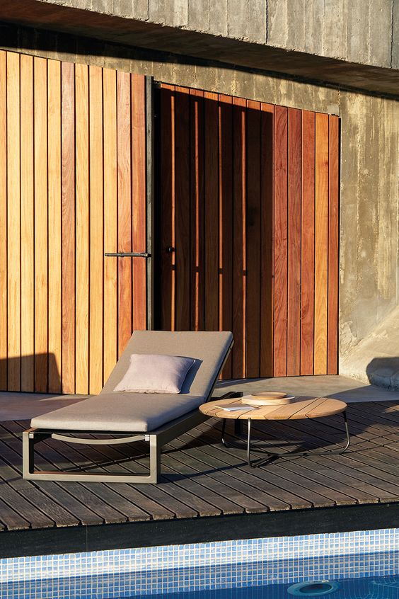 un lettino minimalista con struttura in metallo scuro e tappezzeria color talpa con cuscini si adatta perfettamente a uno spazio moderno o minimalista