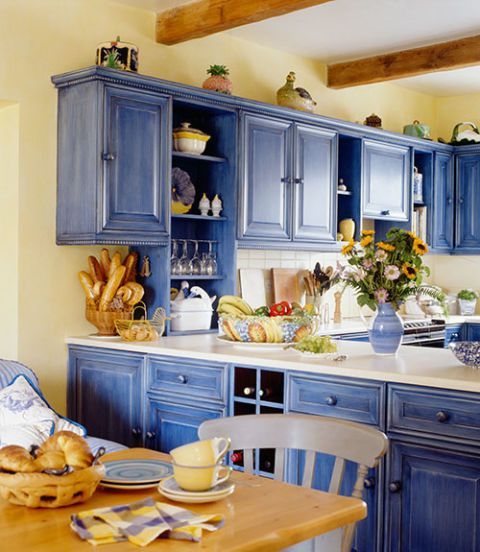 una cucina blu brillante e giallo chiaro rinfrescata con superfici bianche e con legno naturale di colore chiaro